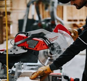 Ayat Timbers worker cutting lumber board with a miter saw at the sawmill